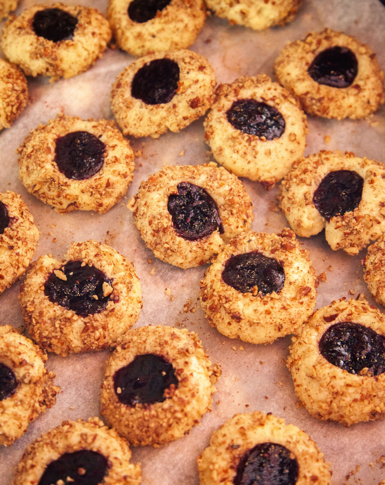 Berry thumbprint cookies sit on parchment paper